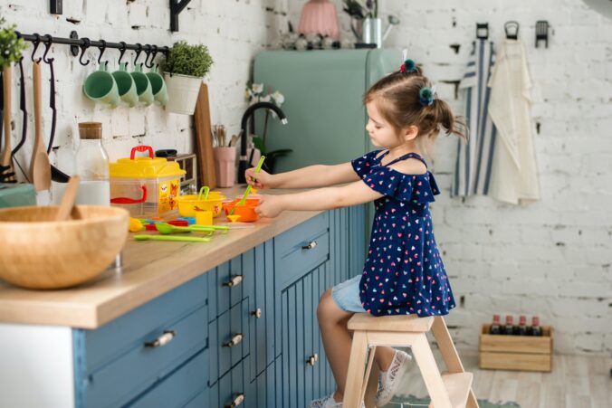 Bilden visar ett barn som leker i köket som har valt barnlås för att barnsäkra hemmet